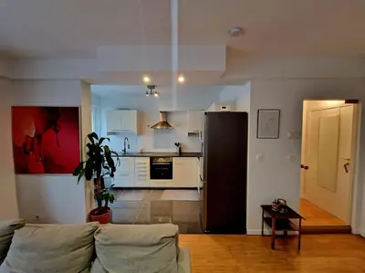 a living room with a couch and a kitchen at Le cocon du midi - Appartement Cosy in Brussels
