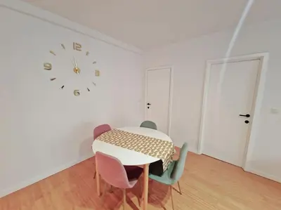 a dining room with a table and chairs and a clock at Le cocon du midi - Appartement Cosy in Brussels