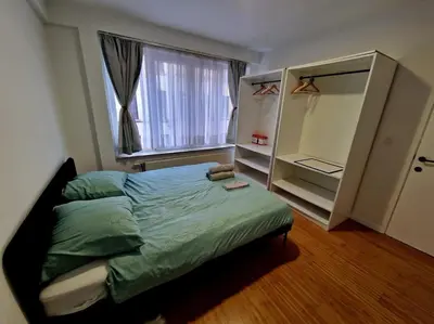 a bedroom with a bed and a large window at Le cocon du midi - Appartement Cosy in Brussels