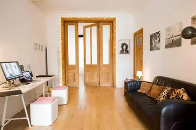 a living room with a couch and a desk with a computer at Grand appartement d'artiste cosy et proche de tout in Brussels