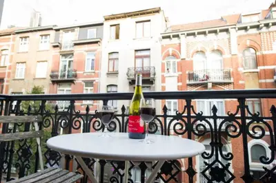 a bottle of wine sitting on a table on a balcony at Grand appartement d'artiste cosy et proche de tout in Brussels