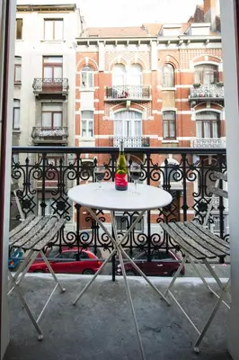 a white table and two chairs on a balcony at Grand appartement d'artiste cosy et proche de tout in Brussels