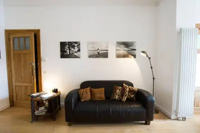 a black leather couch in a living room with paintings at Grand appartement d'artiste cosy et proche de tout in Brussels