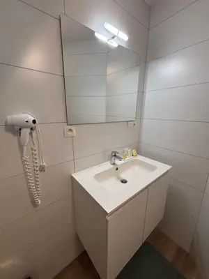 a white bathroom with a sink and a mirror at Hotel La Chaumiere in Asse