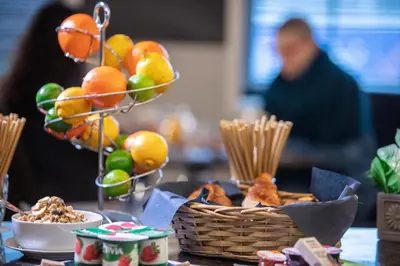 a table topped with a basket of fruit and snacks at Hotel La Chaumiere in Asse