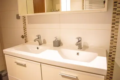 a bathroom sink with two faucets and a mirror at Archimede Guest House in Brussels