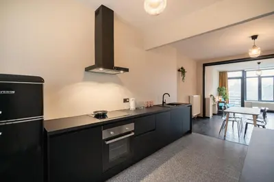 a kitchen with black appliances and a dining room at Charming and Spacious Apartments in the Heart of Antwerp in Antwerp