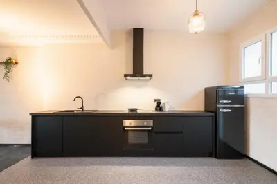 a kitchen with black cabinets and a black refrigerator at Charming and Spacious Apartments in the Heart of Antwerp in Antwerp