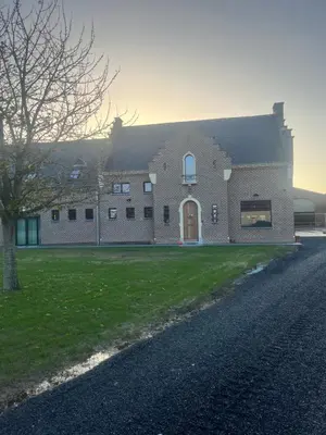 a large brick building with a tree in front of it at B&B Schaliëndak in Kortenberg