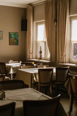 a dining room with tables and chairs and windows at Hotel Kempenrust in Kasterlee
