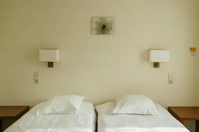 two beds in a room with a clock on the wall at Hotel Kempenrust in Kasterlee