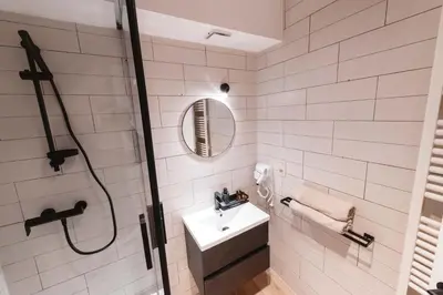a white bathroom with a shower and a sink at K-suites in Brussels