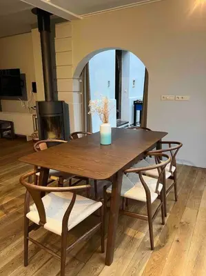 a wooden table with chairs and a vase on top at Charmante maison dans un coin de verdure à Boitsfort in Brussels