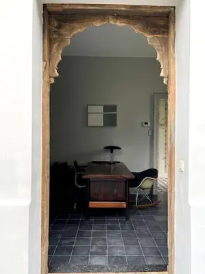 an archway leading into a room with a table and chairs at Charmante maison dans un coin de verdure à Boitsfort in Brussels