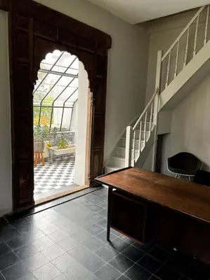 a room with a wooden table and a staircase at Charmante maison dans un coin de verdure à Boitsfort in Brussels
