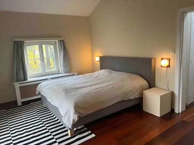 a bedroom with a large bed and a window at Charmante maison dans un coin de verdure à Boitsfort in Brussels