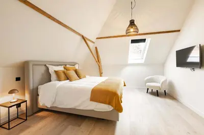 a white bedroom with a bed and a chair at Huis Velzeke in Zottegem
