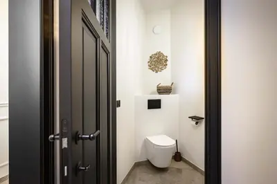 a bathroom with a white toilet and a door at Huis Velzeke in Zottegem