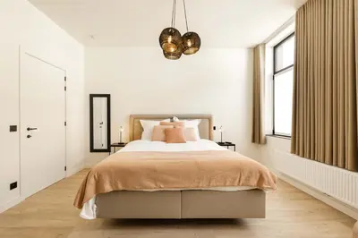 a bedroom with a large bed and a chandelier at Huis Velzeke in Zottegem