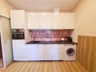 a kitchen with white cabinets and a washing machine at Magnolia Pink Studio New and fully equipped in Brussels