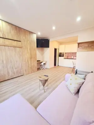 a living room with a white couch and a kitchen at Magnolia Pink Studio New and fully equipped in Brussels