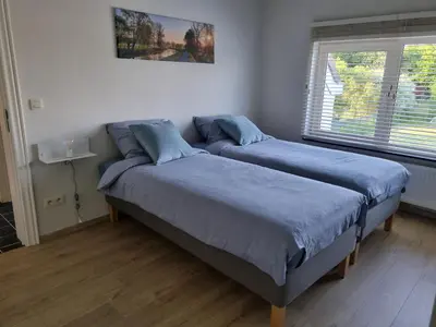 two beds in a bedroom with blue sheets at B&B Krieken de Jour in Ninove