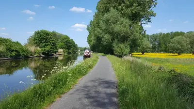 a canal with a boat on the water and trees at B&B Krieken de Jour in Ninove