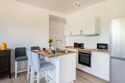 a kitchen with white cabinets and a wooden counter top at Brussels EU Design Residence in Brussels