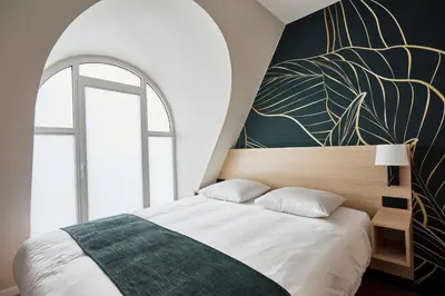 a bedroom with a large bed with a large window at Georges Henri Aparthotel in Brussels
