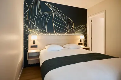 a bedroom with a large bed with a large plant on the wall at Georges Henri Aparthotel in Brussels