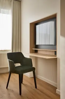 a green chair in a room with a television at Georges Henri Aparthotel in Brussels