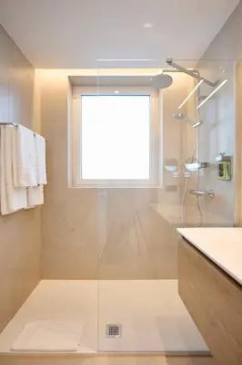 a bathroom with a shower and a sink and a window at Georges Henri Aparthotel in Brussels