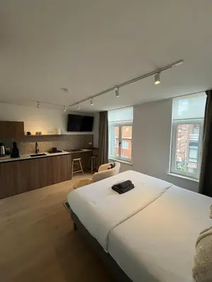 a bedroom with a large white bed and a kitchen at Business Accommodation 'Natural Living' Nomad in Geel
