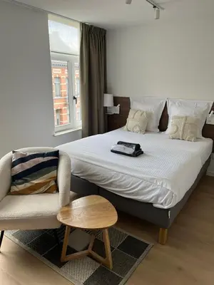 a bedroom with a large bed and a chair at Business Accommodation 'Natural Living' Nomad in Geel