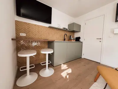 a kitchen with two stools and a tv on the wall at Business Accommodation 'Scandinavian Living' Nomad in Geel