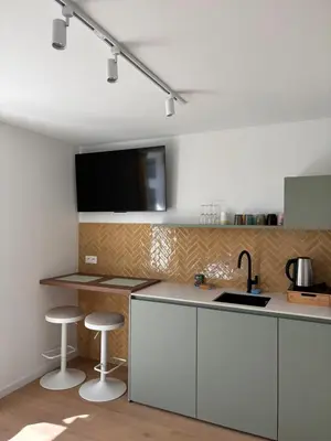 a kitchen with white cabinets and a tv on the wall at Business Accommodation 'Scandinavian Living' Nomad in Geel
