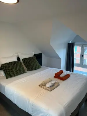 a white bed with two pillows and towels on it at Business Accommodation 'Loft' Intimate in Geel