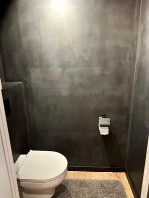 a bathroom with a toilet and a gray wall at Luxury Apartment with Cosy Garden! in Ghent