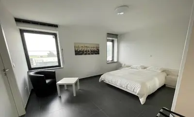 a bedroom with a bed and a chair and a window at Molenbaan28 in Merchtem