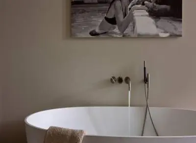 a bath tub in a bathroom with a picture on the wall at De Gulden Poorte, a LXRYHOME Hotel Collection in Antwerp