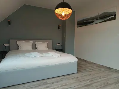 a bedroom with a white bed and a chandelier at Lichtrijke woning vlakbij Leuven in Herent