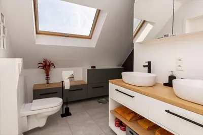 a bathroom with two sinks and a toilet and a window at Lichtrijke woning vlakbij Leuven in Herent
