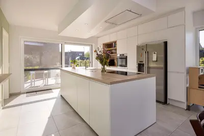 a large kitchen with white cabinets and a large window at Lichtrijke woning vlakbij Leuven in Herent