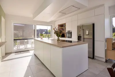 a large kitchen with white cabinets and a counter top at Lichtrijke woning vlakbij Leuven in Herent
