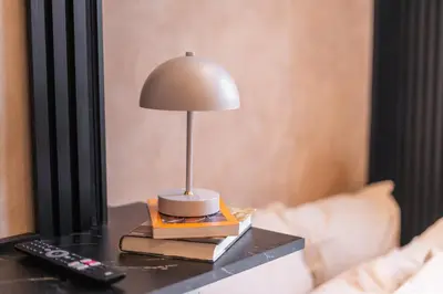 a lamp on a table with books and a remote control at Spacious Shared 5BR Apt in the Heart of Gent in Ghent