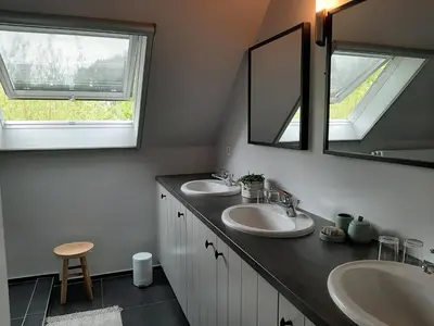 a bathroom with two sinks and a mirror at B&B De Levensboom in Tessenderlo