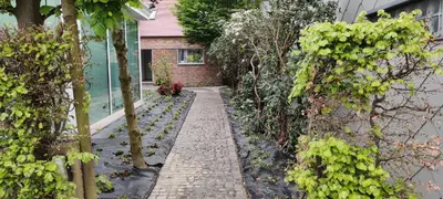 a garden with a brick walkway next to a house at Docs House in Wetteren