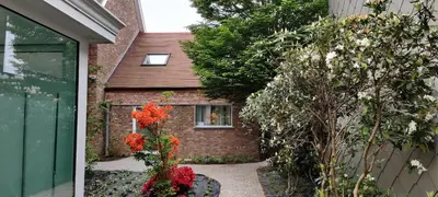 a brick house with a window and flowers in front of it at Docs House in Wetteren