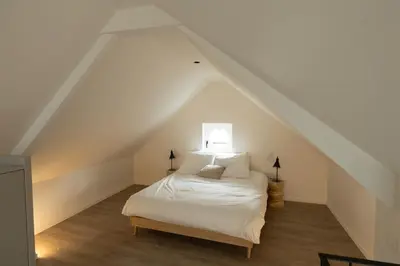 a bedroom with a white bed in a attic at Zeer unieke vakantiewoning in Herentals