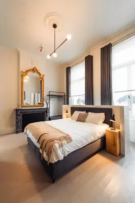 a bedroom with a large bed and a mirror at Luxeverblijf B&B het Wevershuis in Herentals